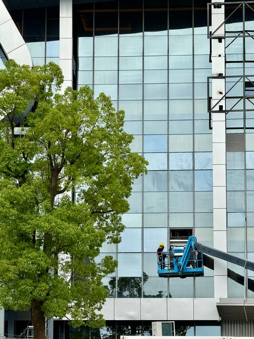 Free Construction worker on lift beside modern building facade in Shanghai, China. Stock Photo