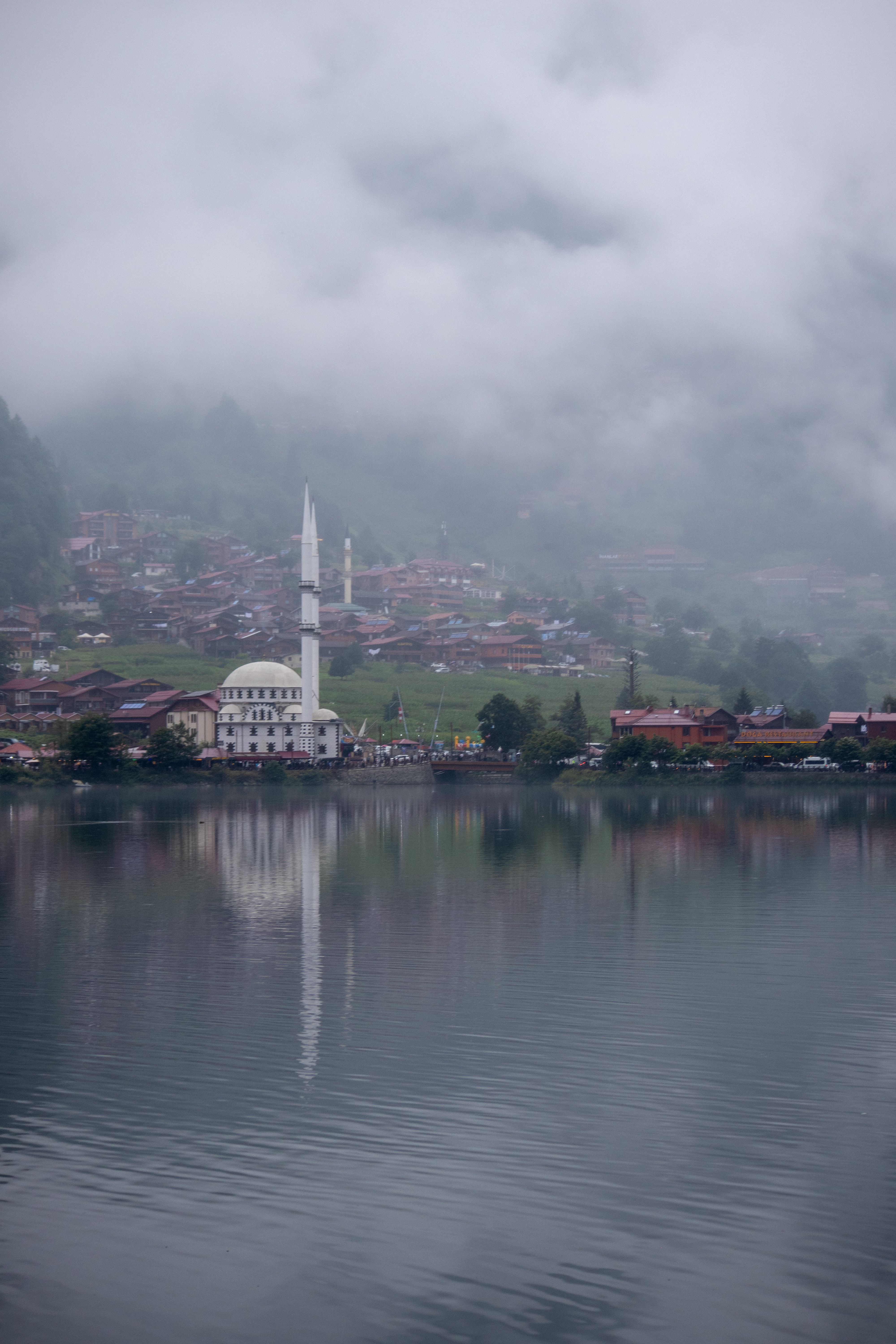 Peaceful Uzungöl lake with mosque and village shrouded in mist, Trabzon, Türkiye.
