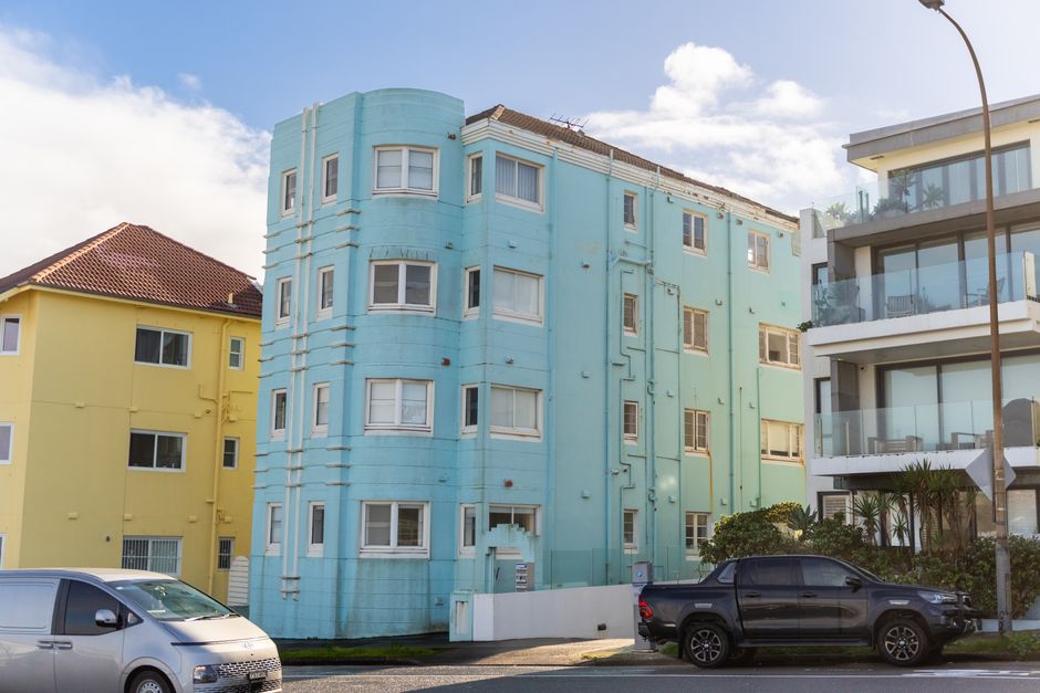 Vibrant pastel-colored apartment buildings on a sunny day with vehicles parked outside.