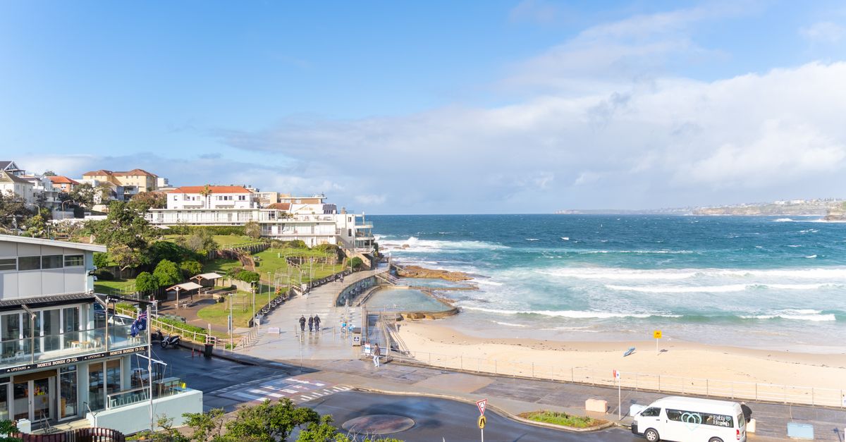 Breathtaking view of Bondi Beach with ocean waves and a coastal promenade under a clear sky.