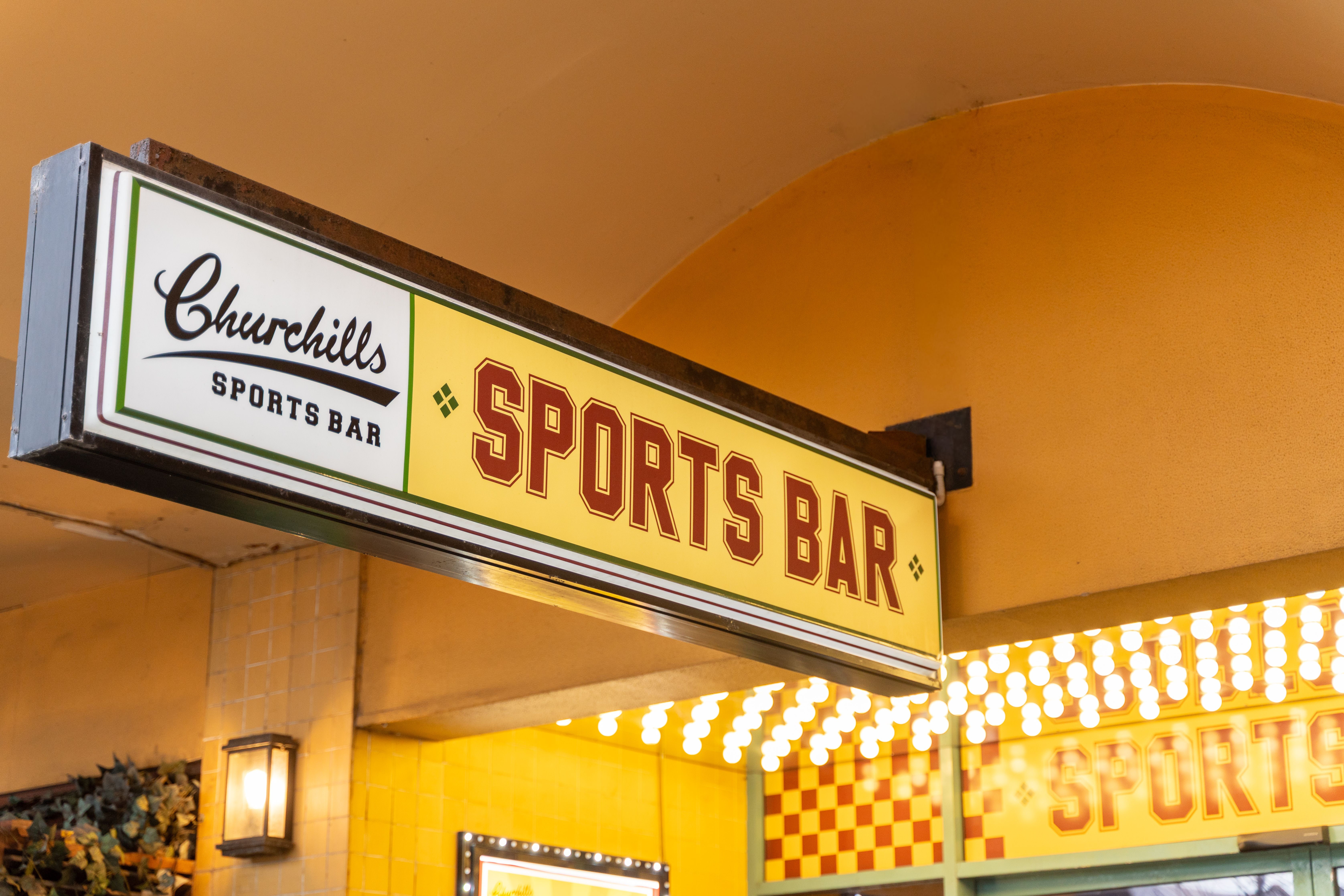 Retro-style sports bar sign with bright lighting, showcasing a welcoming entrance.