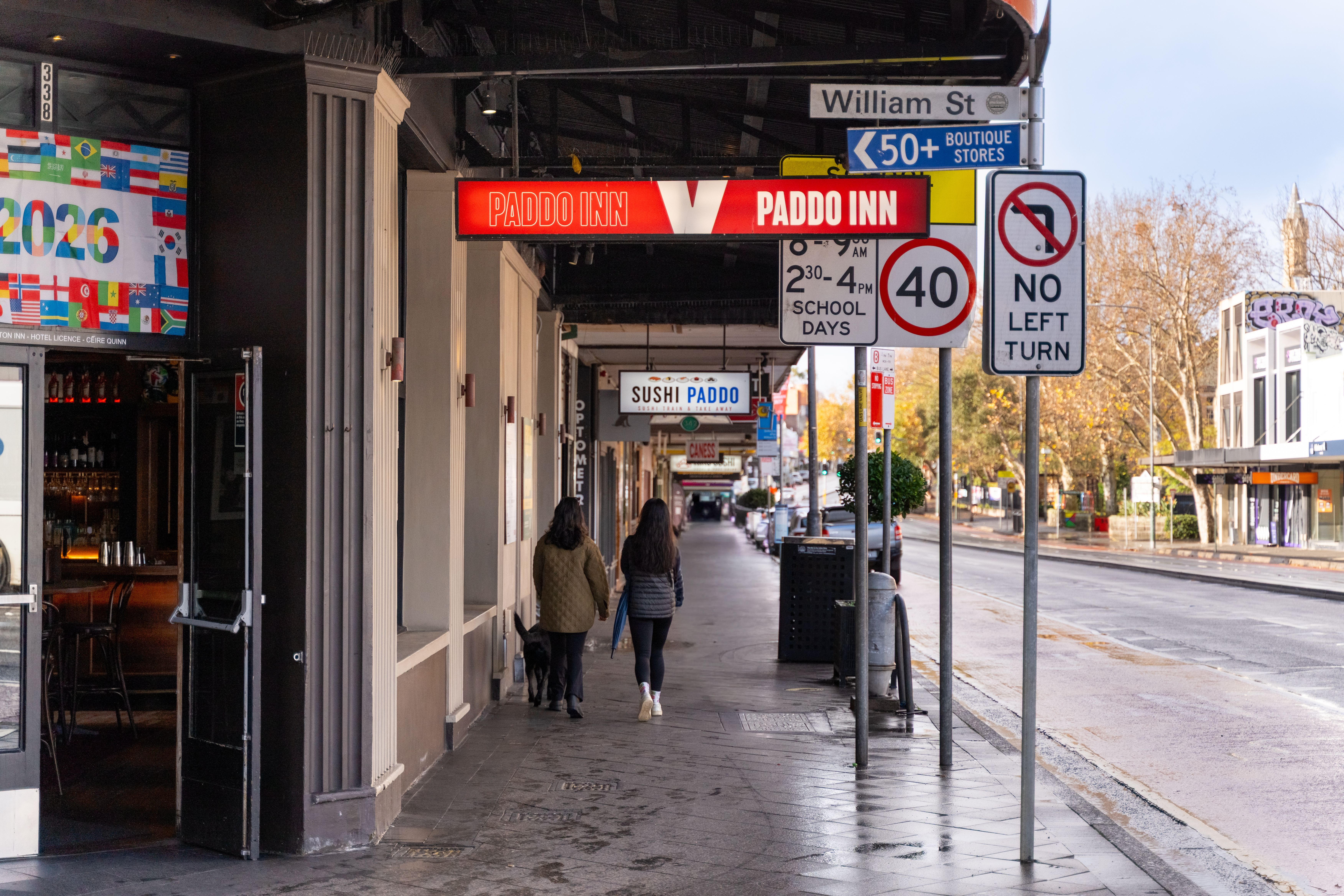 Urban street scene in Paddington, showcasing colorful storefronts and pedestrians in the vibrant commercial area.