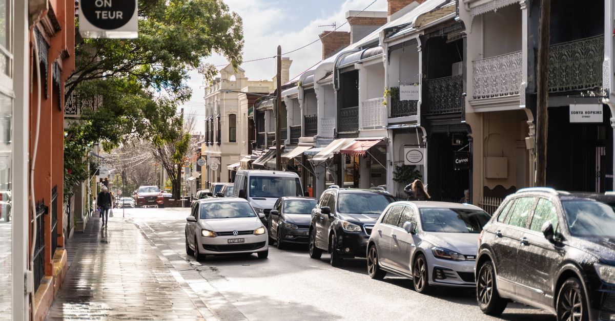 A bustling urban street with parked cars, pedestrians, and charming architectural details.