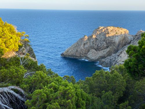 Free Breathtaking view of a rocky coastline with clear blue waters and lush greenery. Stock Photo