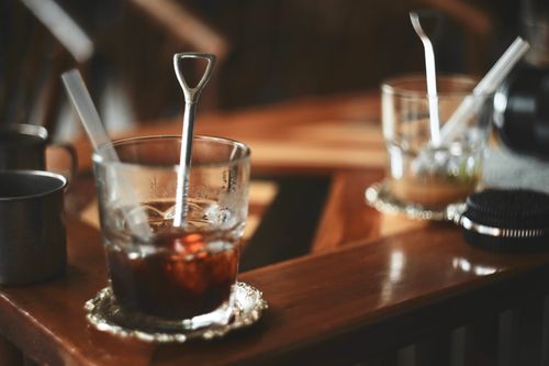 Free Artistic shot of two drink glasses with stirring spoons in a cozy café setting. Stock Photo