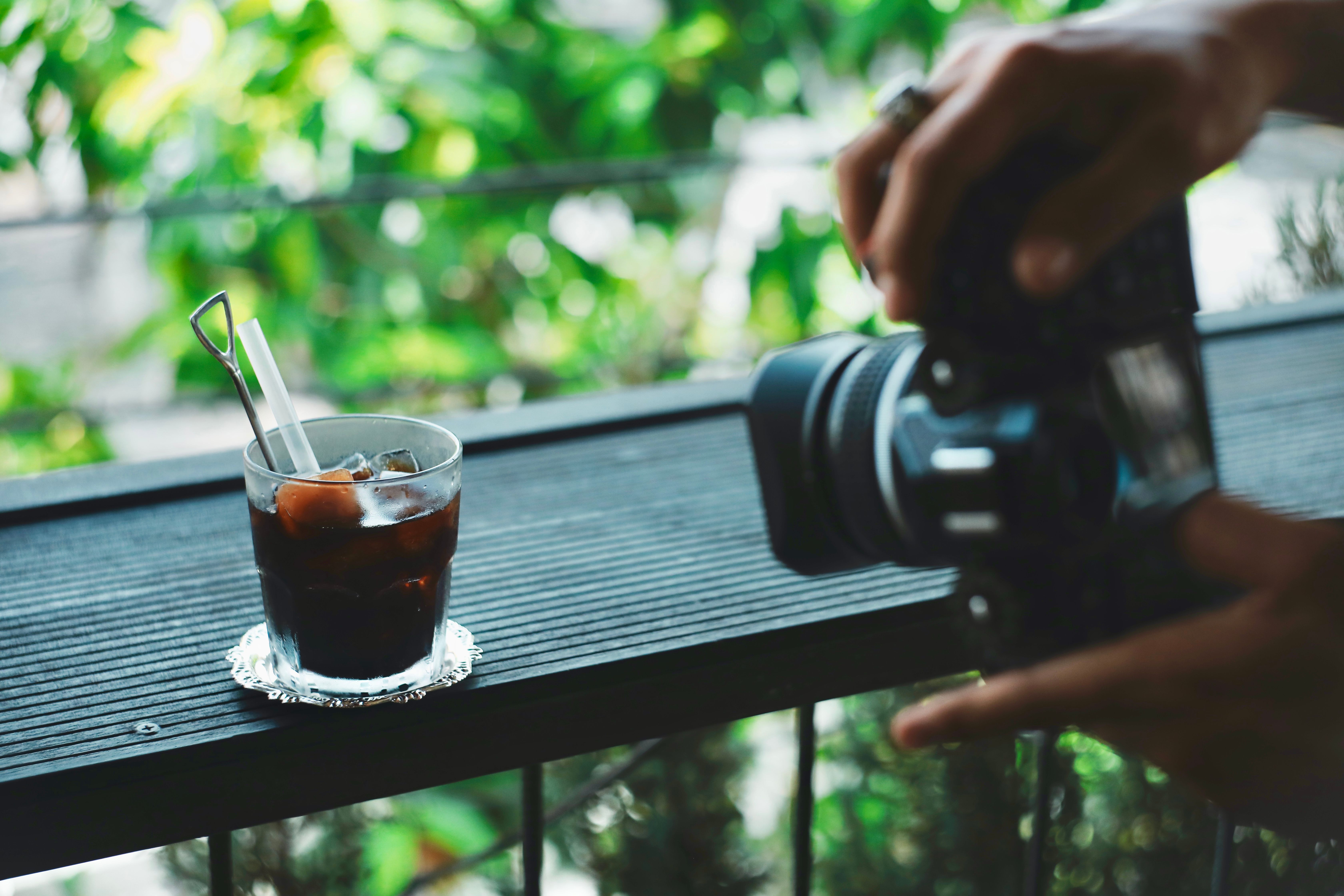 A close-up of iced coffee on a balcony captured by a photographer's camera.
