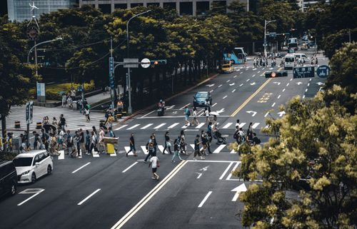 Free Crowded crosswalk in city with diverse pedestrians and vehicles at intersection. Stock Photo