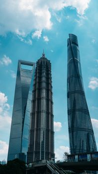 The Shanghai Tower, Jin Mao Tower, and Shanghai World Financial Center under a vibrant blue sky.