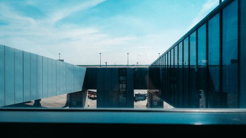 Free A view of a sleek airport skybridge with blue reflective glass under a clear sky. Stock Photo