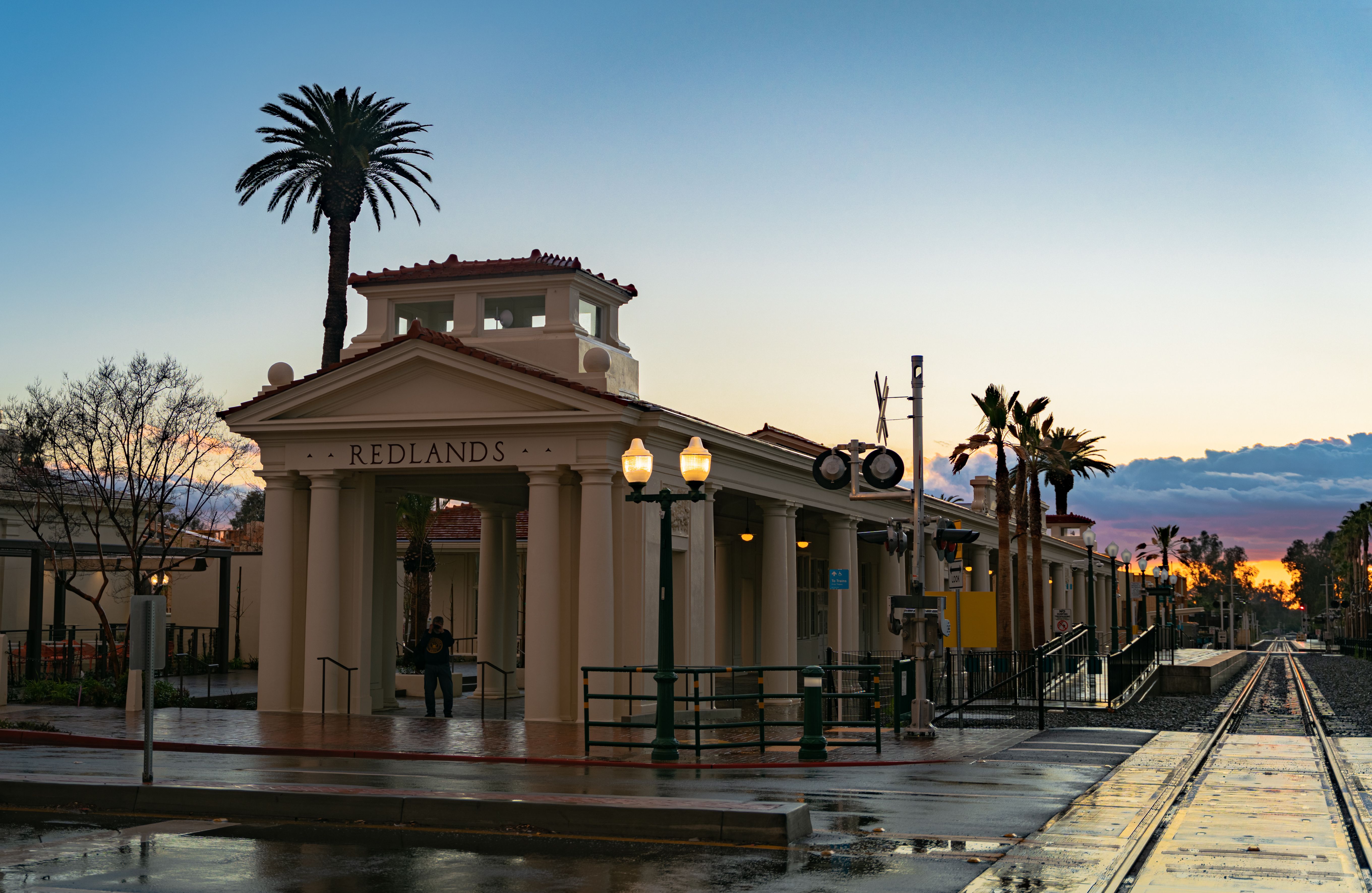 The historic Redlands station captured at dusk with palm trees and wet tracks.