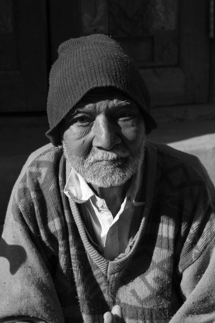 Black and white portrait of an elderly man with facial hair and knitted hat.