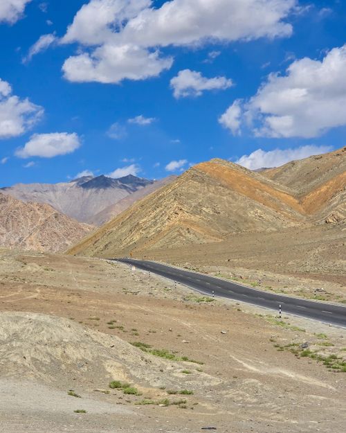 Free A winding road amidst barren mountains under a vibrant blue sky, perfect for travel adventures. Stock Photo
