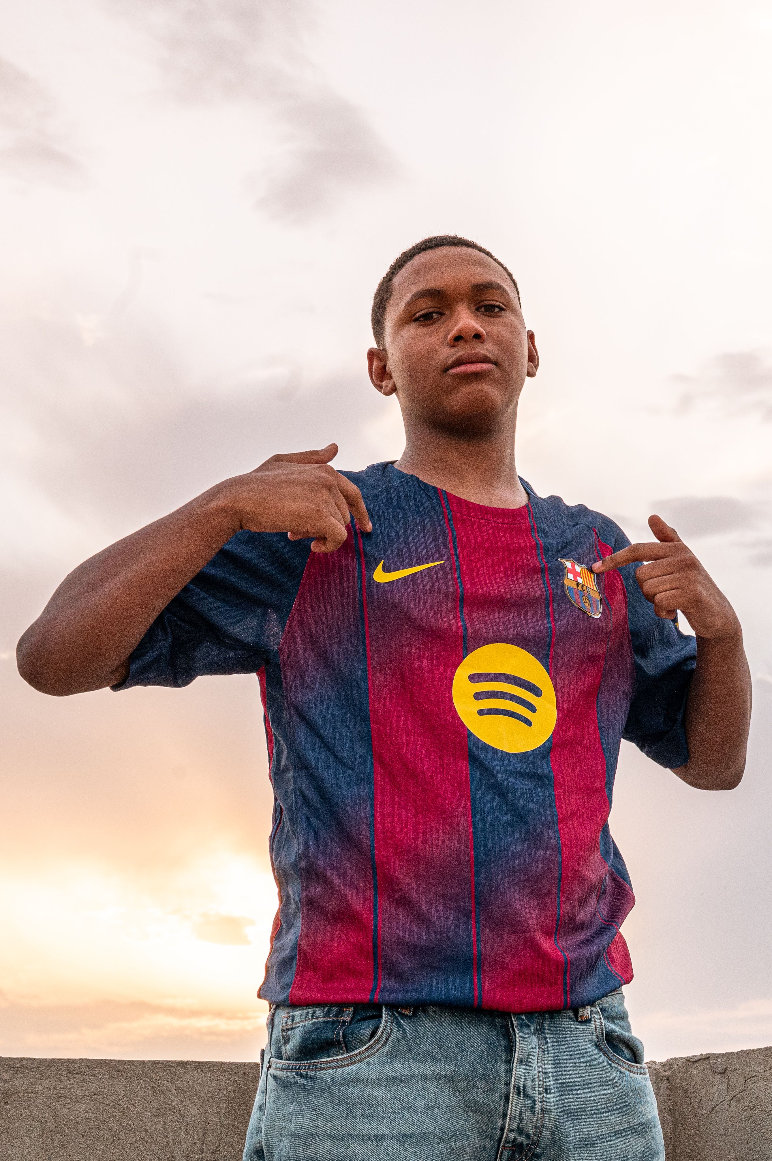 Teenager posing confidently in sports jersey outdoors, showcasing team pride.