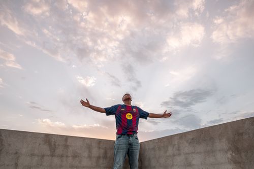 Free Man standing with outstretched arms looking at the sky, under a dramatic cloudscape. Stock Photo