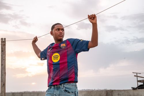 Free Teenager outdoors in a soccer jersey at sunset, standing confidently. Stock Photo