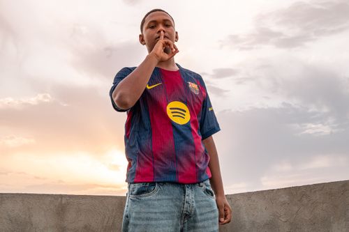 Free A young man wearing a sports jersey gestures to the camera at sunset. Stock Photo