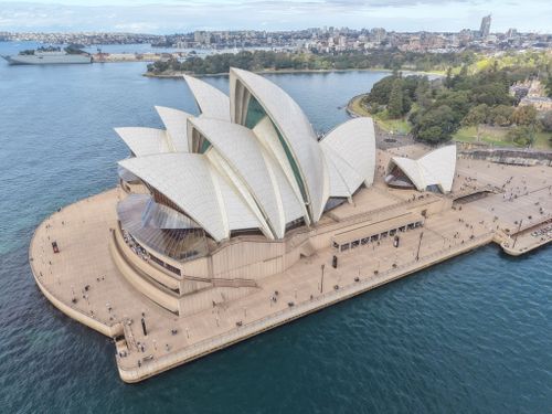Free Stunning aerial shot of the iconic Sydney Opera House surrounded by water and cityscape. Stock Photo