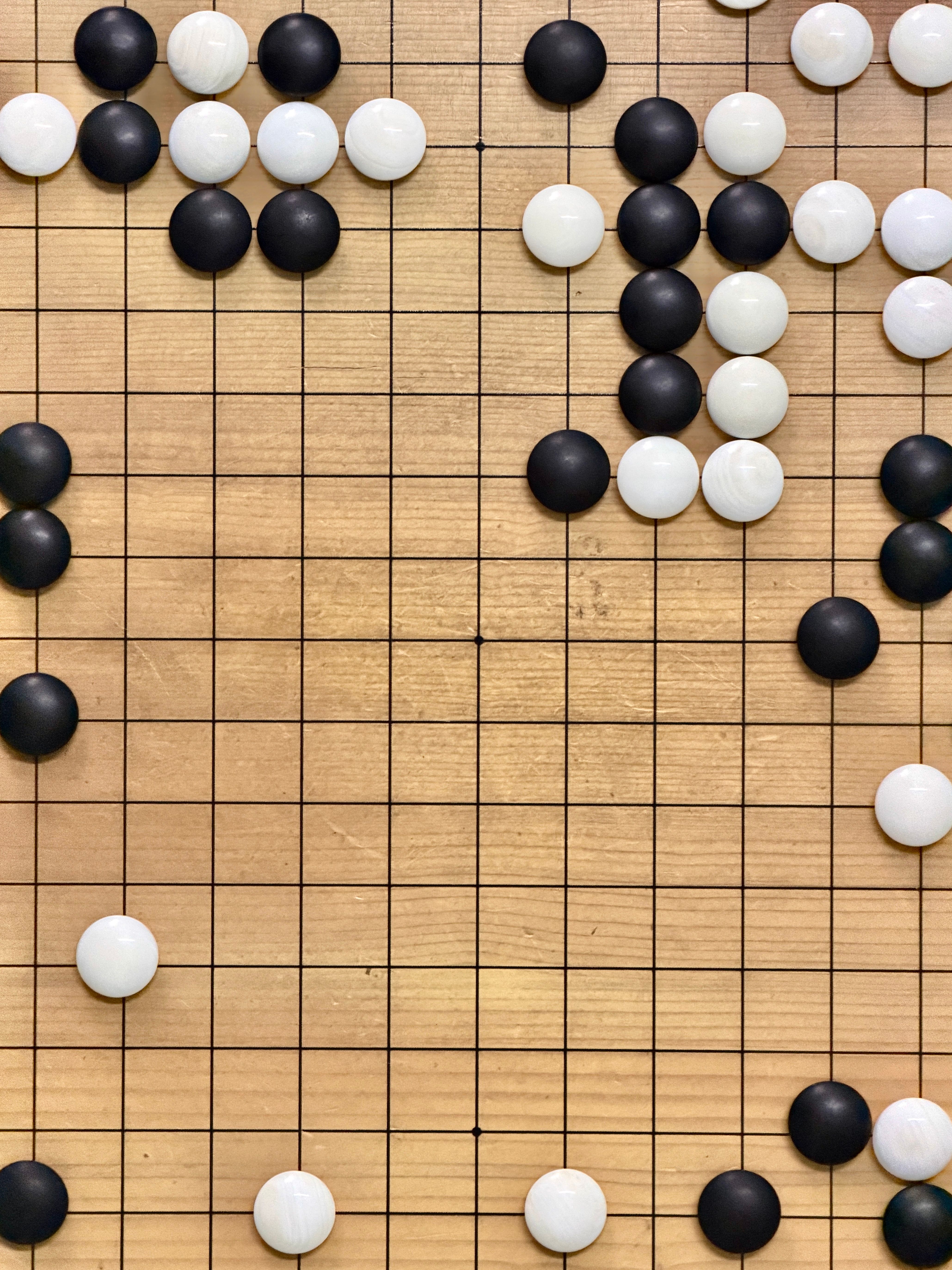 Close-up of a Goban with black and white go stones in strategic formation.