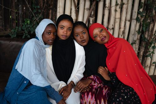 Free Four women in vibrant hijabs embrace, showing sisterhood and diversity outdoors. Stock Photo
