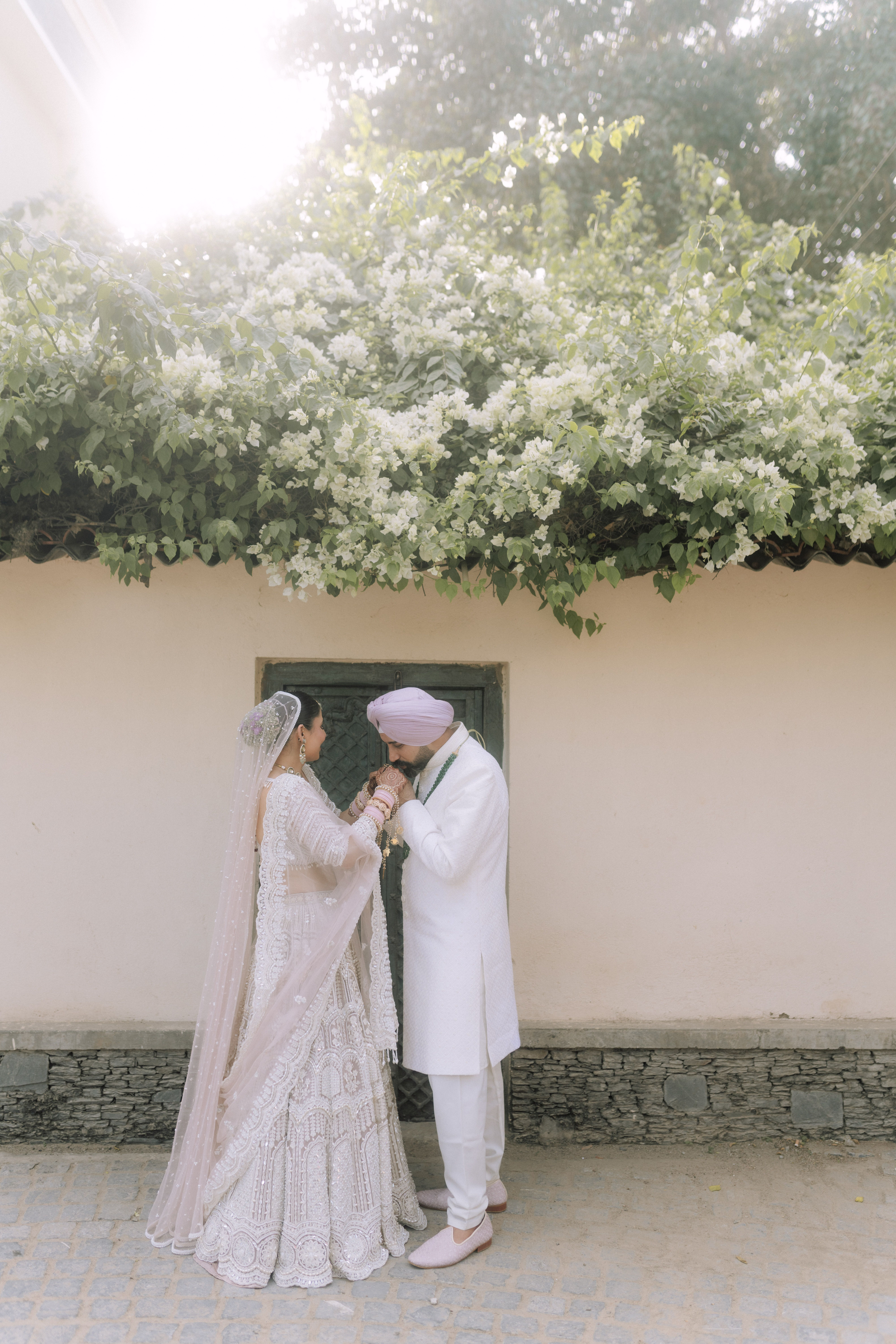 A romantic portrait of an Indian wedding couple in traditional attire, framed by lush white flowers.