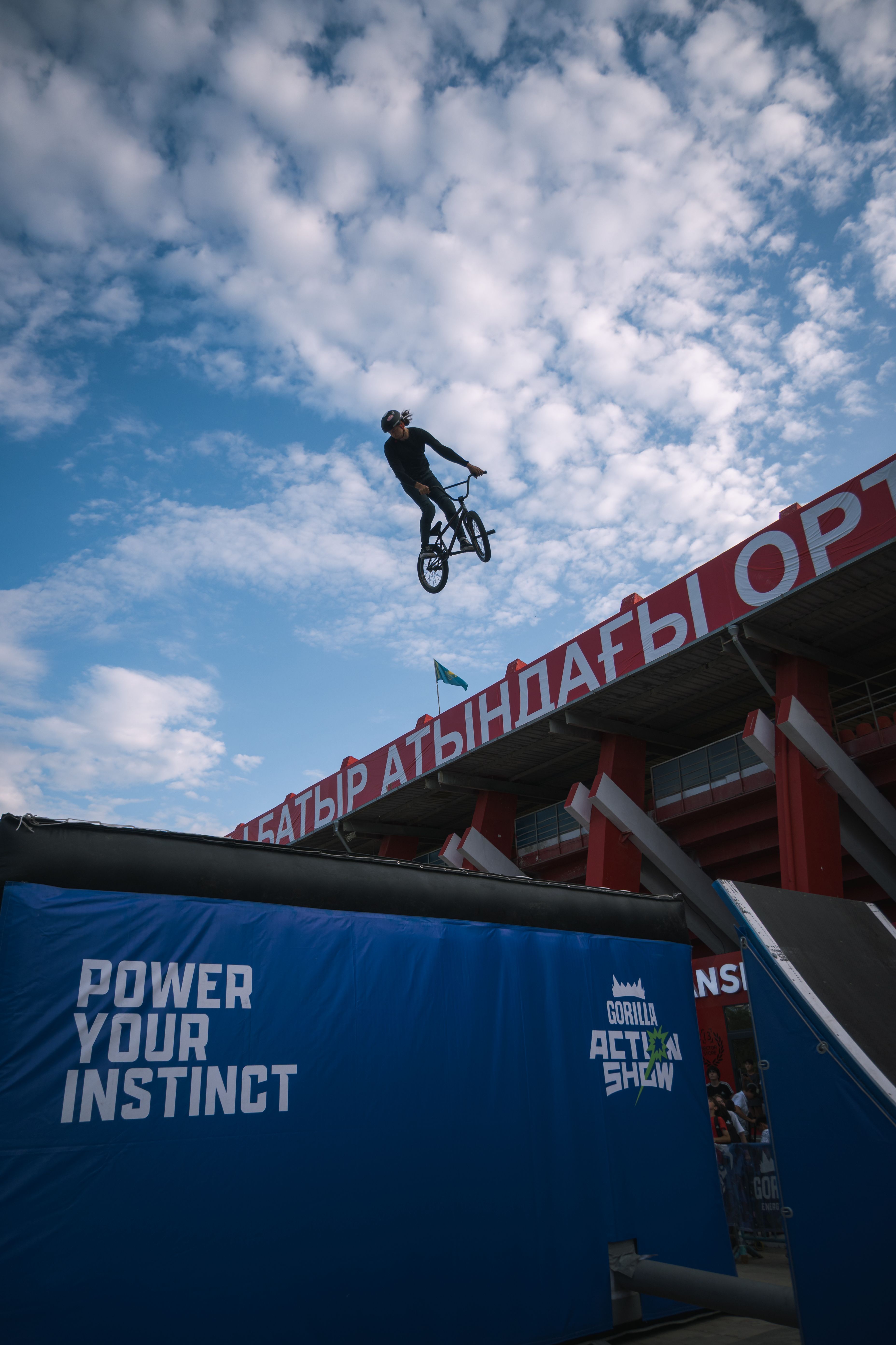 High-flying BMX stunt against a cloudy sky at an adrenaline-fueled outdoor action show.