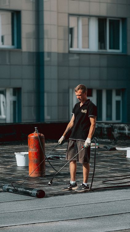 Roofer applying a roofing membrane on a flat roof in daylight