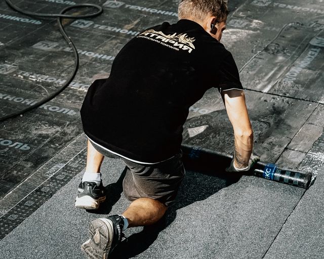 New roofing being installed Roofer installing asphalt roofing material under bright sun