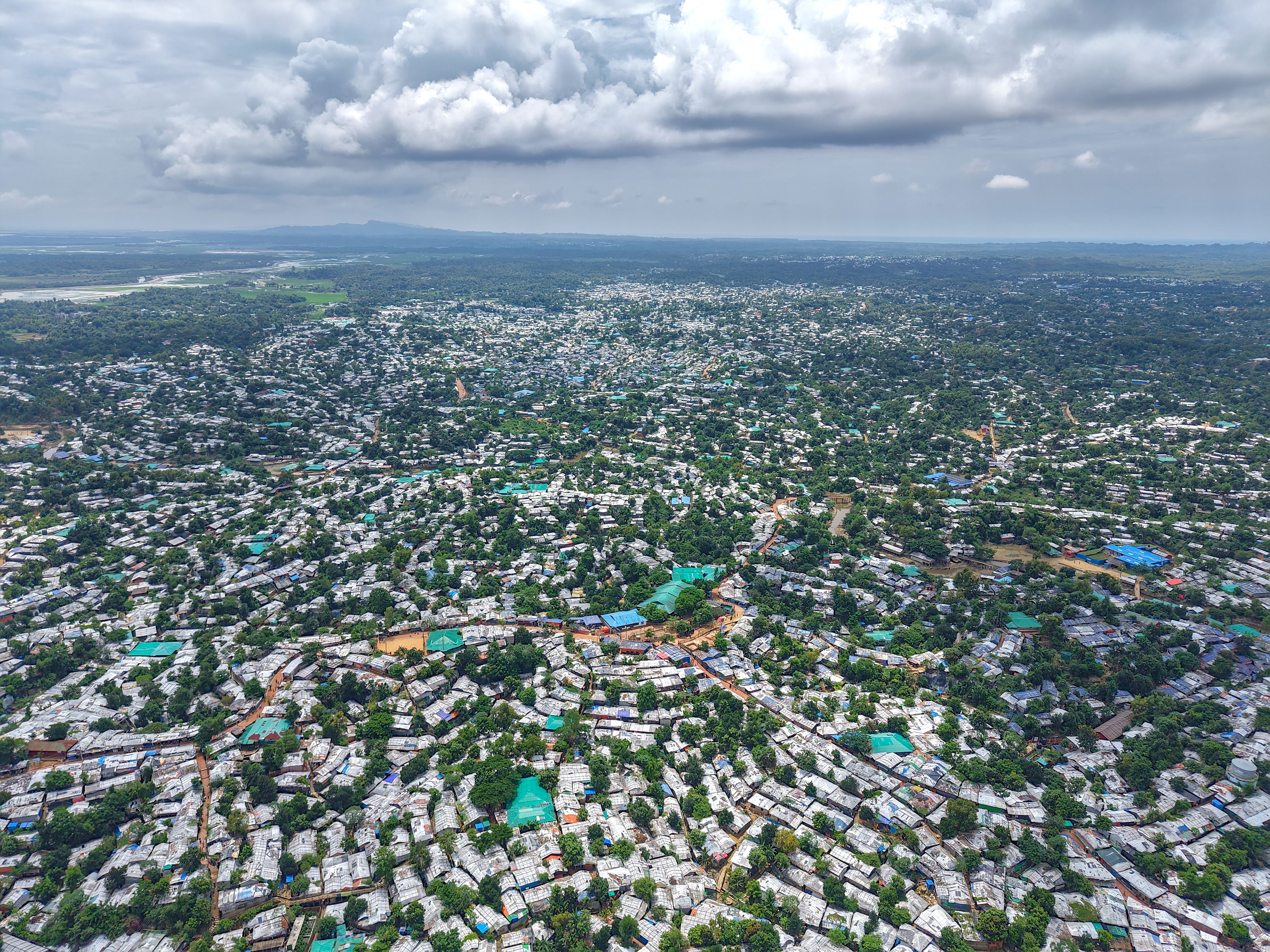 Expansive aerial view of a crowded refugee settlement in Bangladesh surrounded by lush greenery.