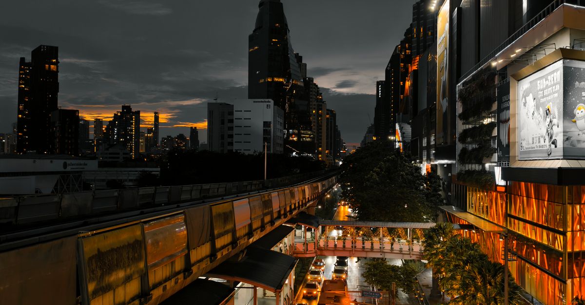 Dynamic city skyline at dusk featuring a bustling elevated train and illuminated buildings.