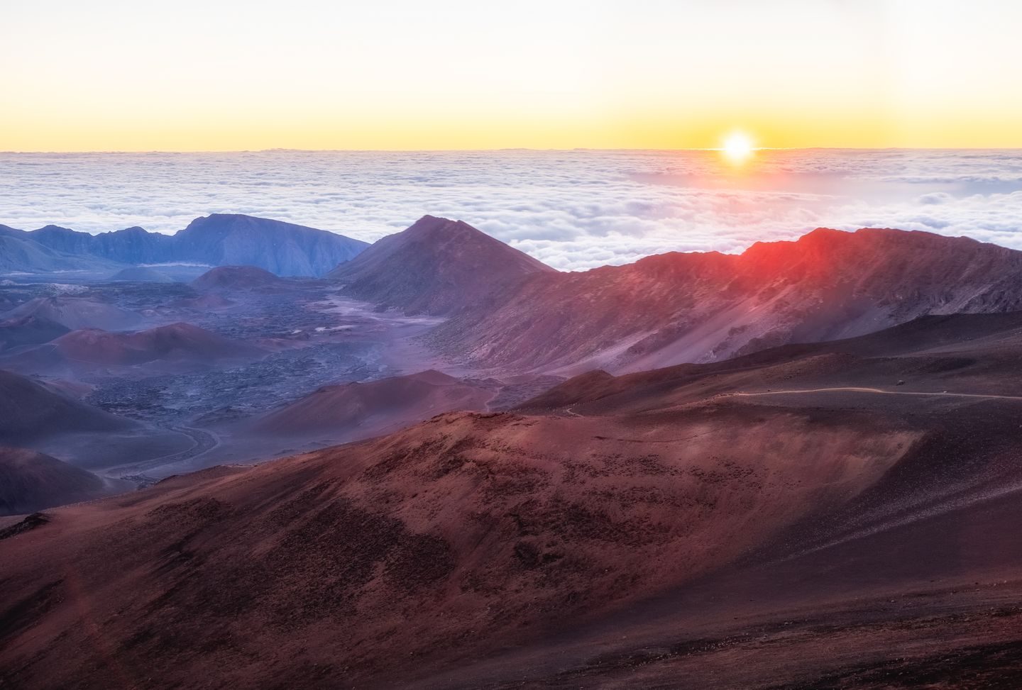 Sunrise breaking above the clouds from the summit of Haleakalā on Maui