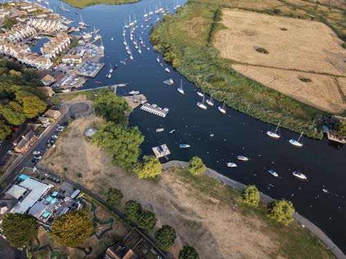 Free Aerial view of a marina with yachts, residential area, and fields. Stock Photo
