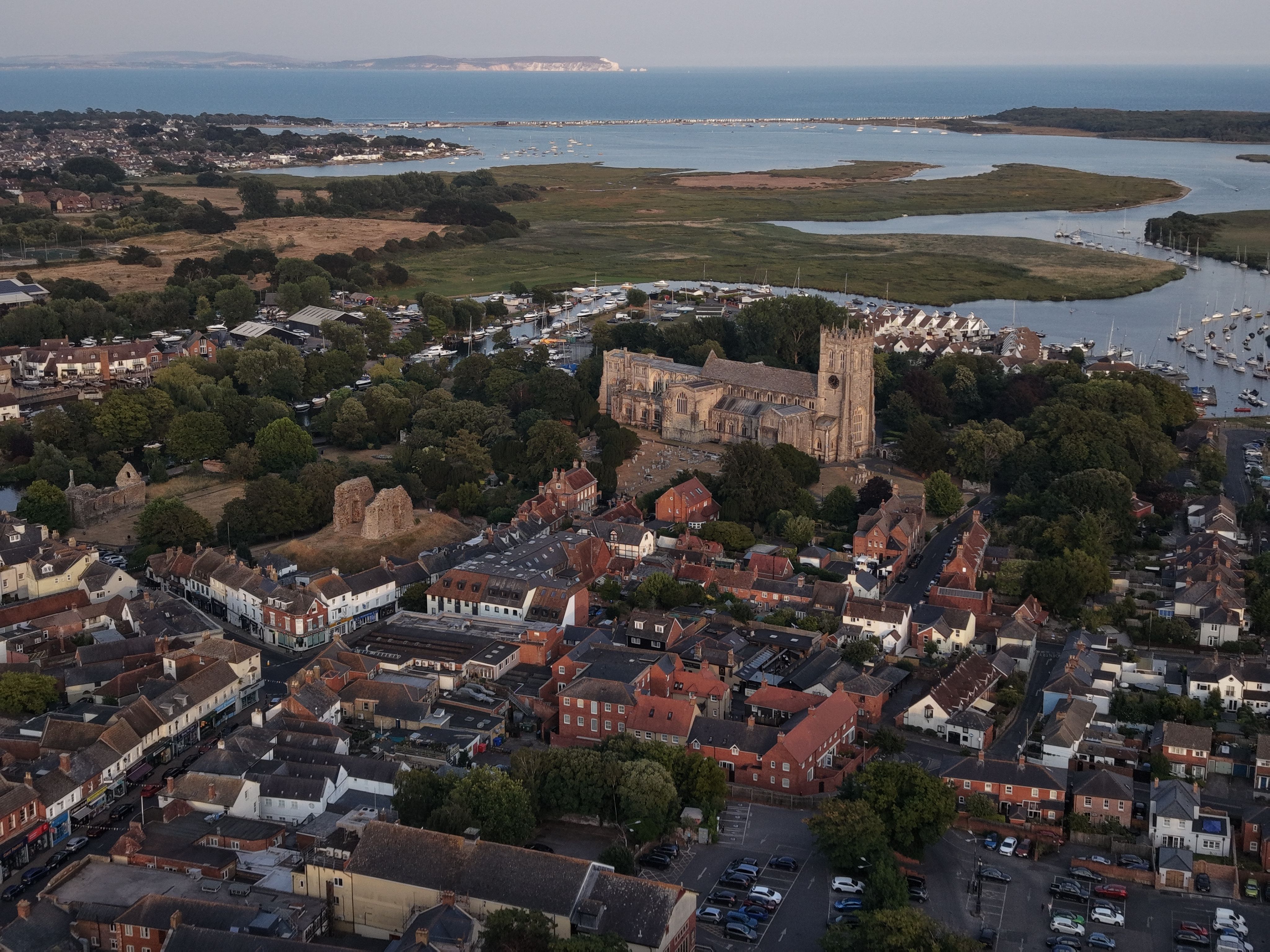 Aerial view showcasing a historic church amidst a coastal town and nearby marina.