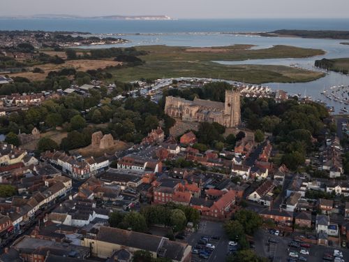 Free Aerial view showcasing a historic church amidst a coastal town and nearby marina. Stock Photo