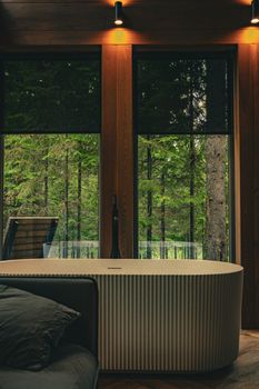 Luxurious indoor bathtub with a serene forest view through large windows.