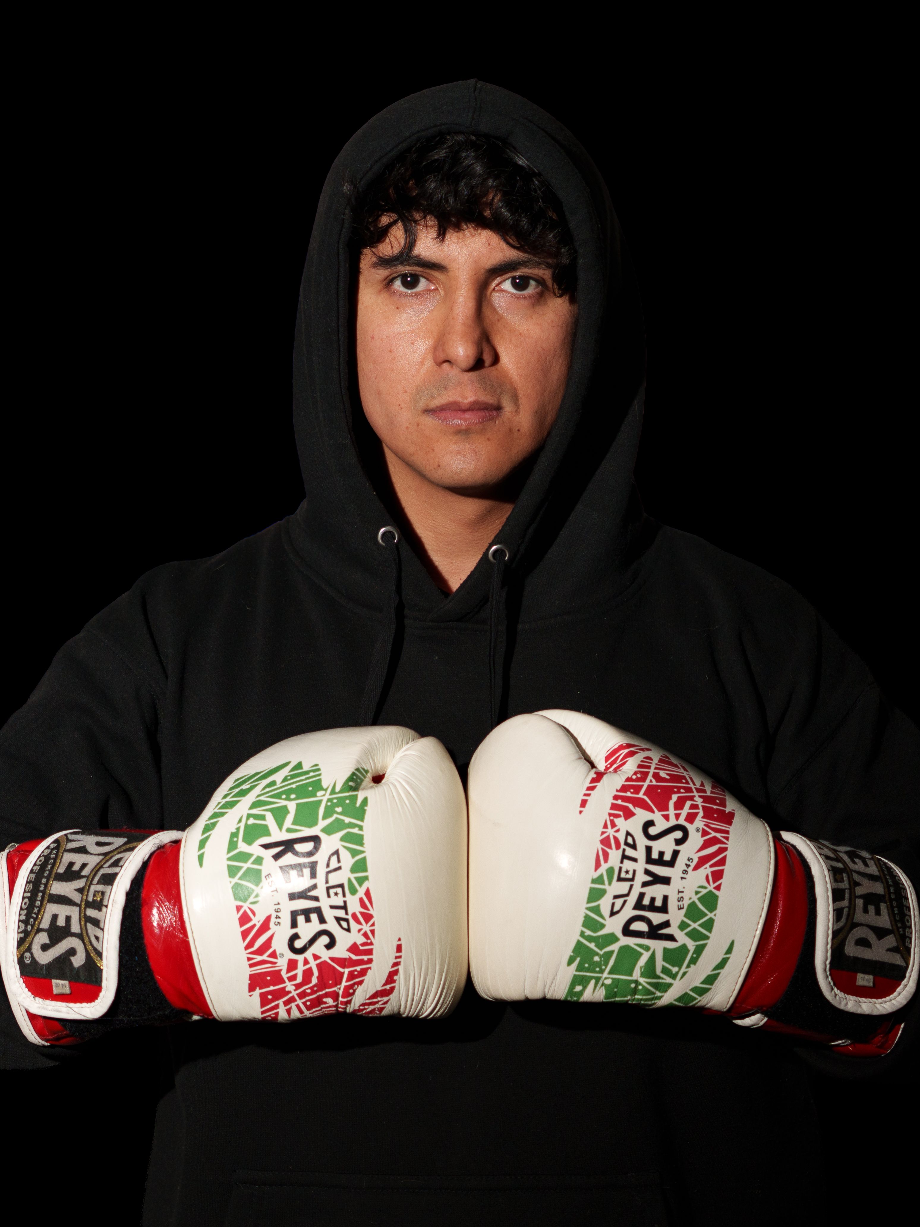 Male boxer wearing a hoodie and Mexican flag gloves ready for a match.