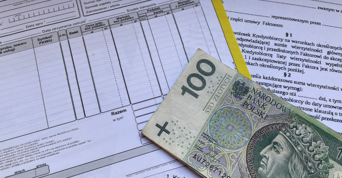 100 Polish zloty bill on top of financial documents and invoices on desk.
