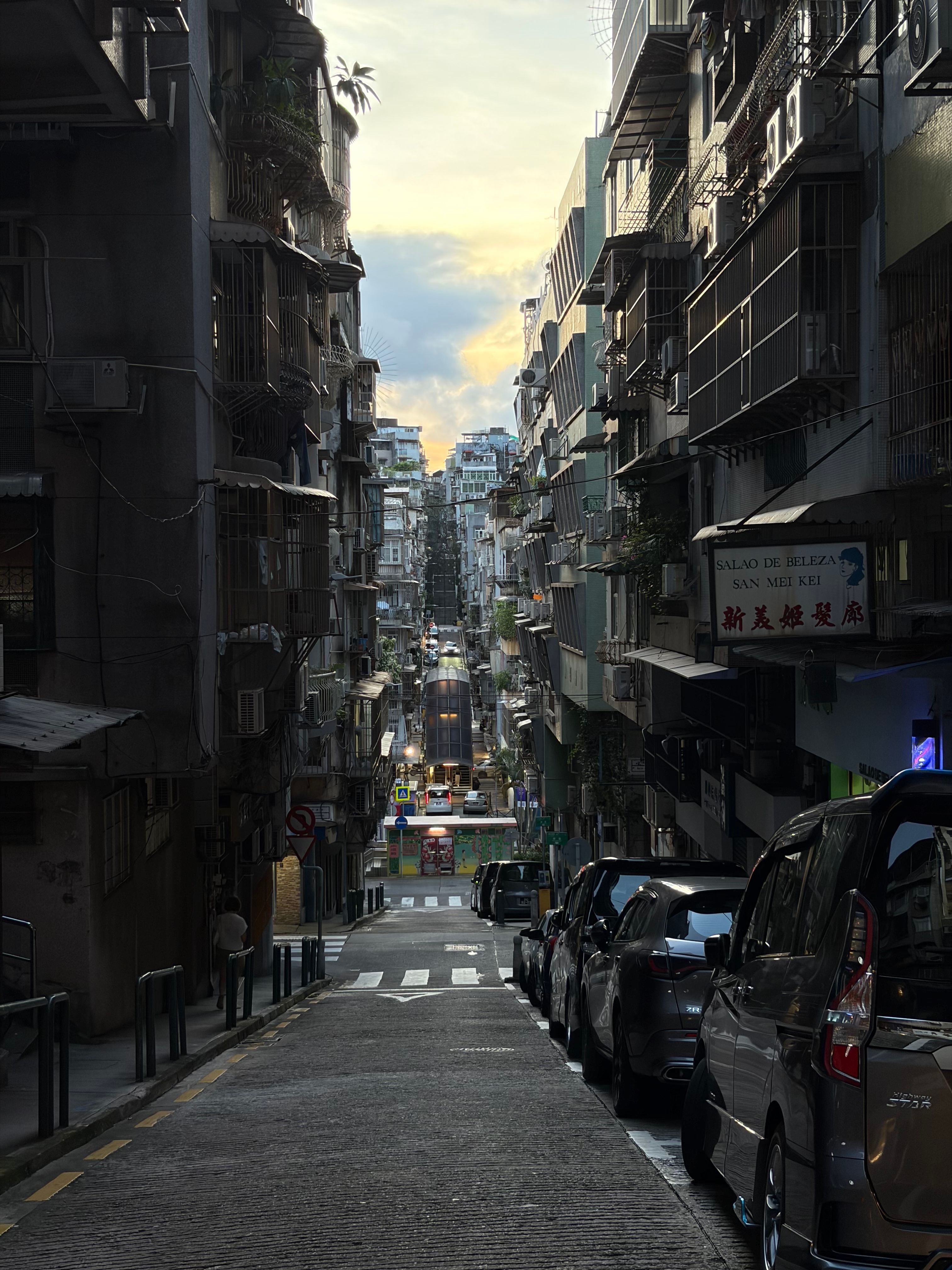 Charming view of a dense urban street in Macao during sunset, showcasing captivating architecture and bustling city life.