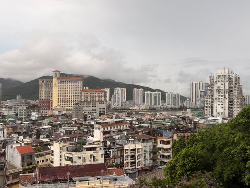Free Explore the contrasting skyline of Macao, showcasing both historic buildings and modern skyscrapers under a cloudy sky. Stock Photo