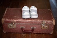 一双可爱的灰色婴儿运动鞋被放在一个古董手提箱里，完美融合了怀旧与青春