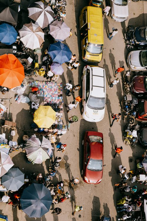 Free Overhead view of a bustling market street in Lagos, Nigeria with colorful umbrellas and vehicles. Stock Photo