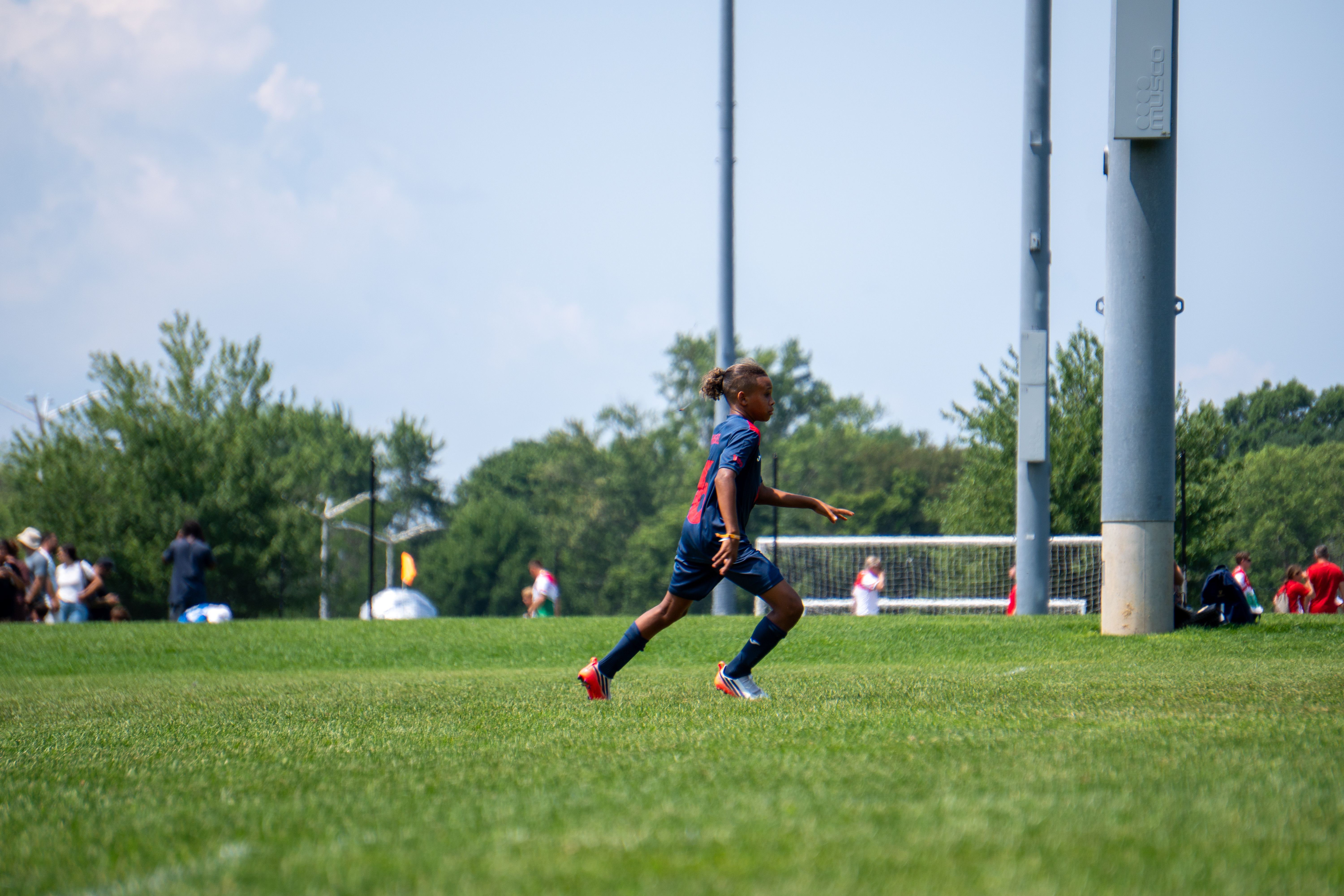 A young soccer player in action on a sunny day in New York City park.