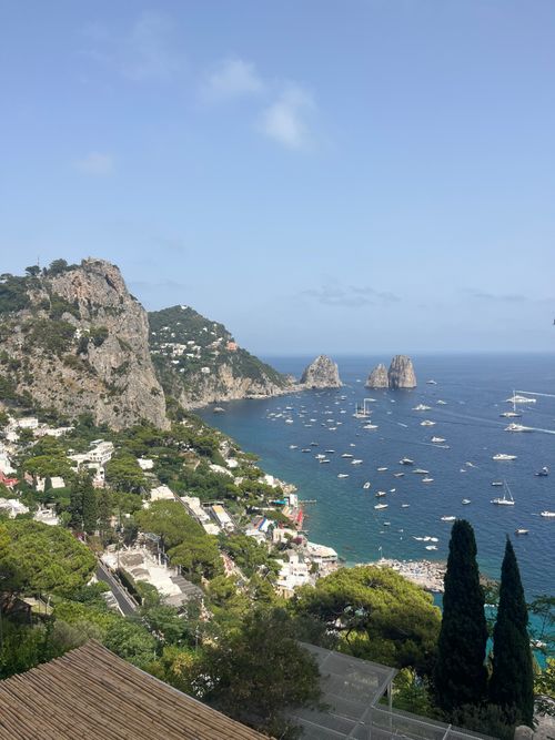 Free A breathtaking view of the iconic Faraglioni rocks in Capri, Italy, surrounded by azure waters and lush greenery. Stock Photo