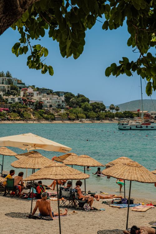 Free Relaxing beach scene with sunbathers and boats in Bodrum, Turkey. Stock Photo