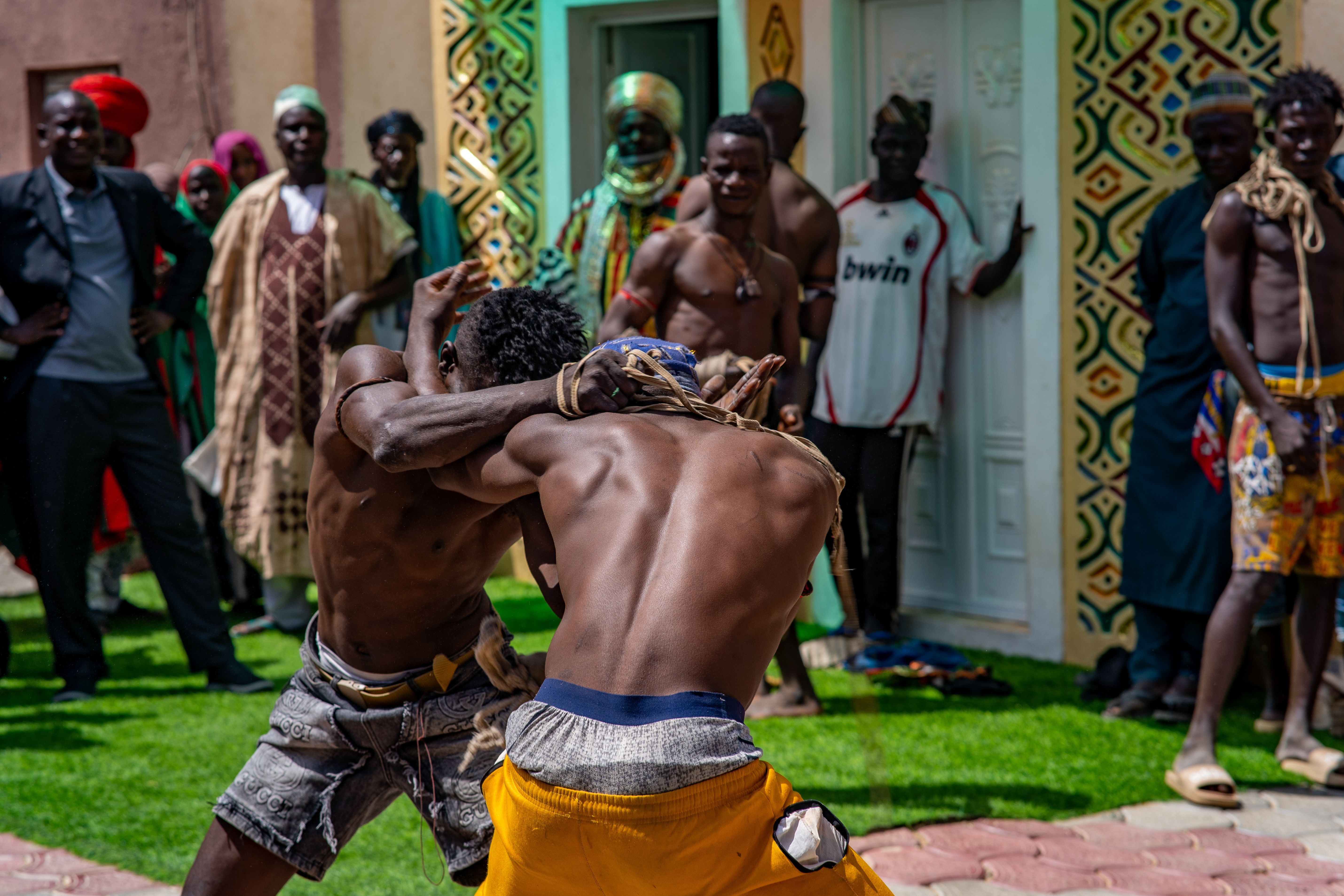 Energetic traditional wrestling scene in Rano, Nigeria with vibrant cultural attire and spectators.