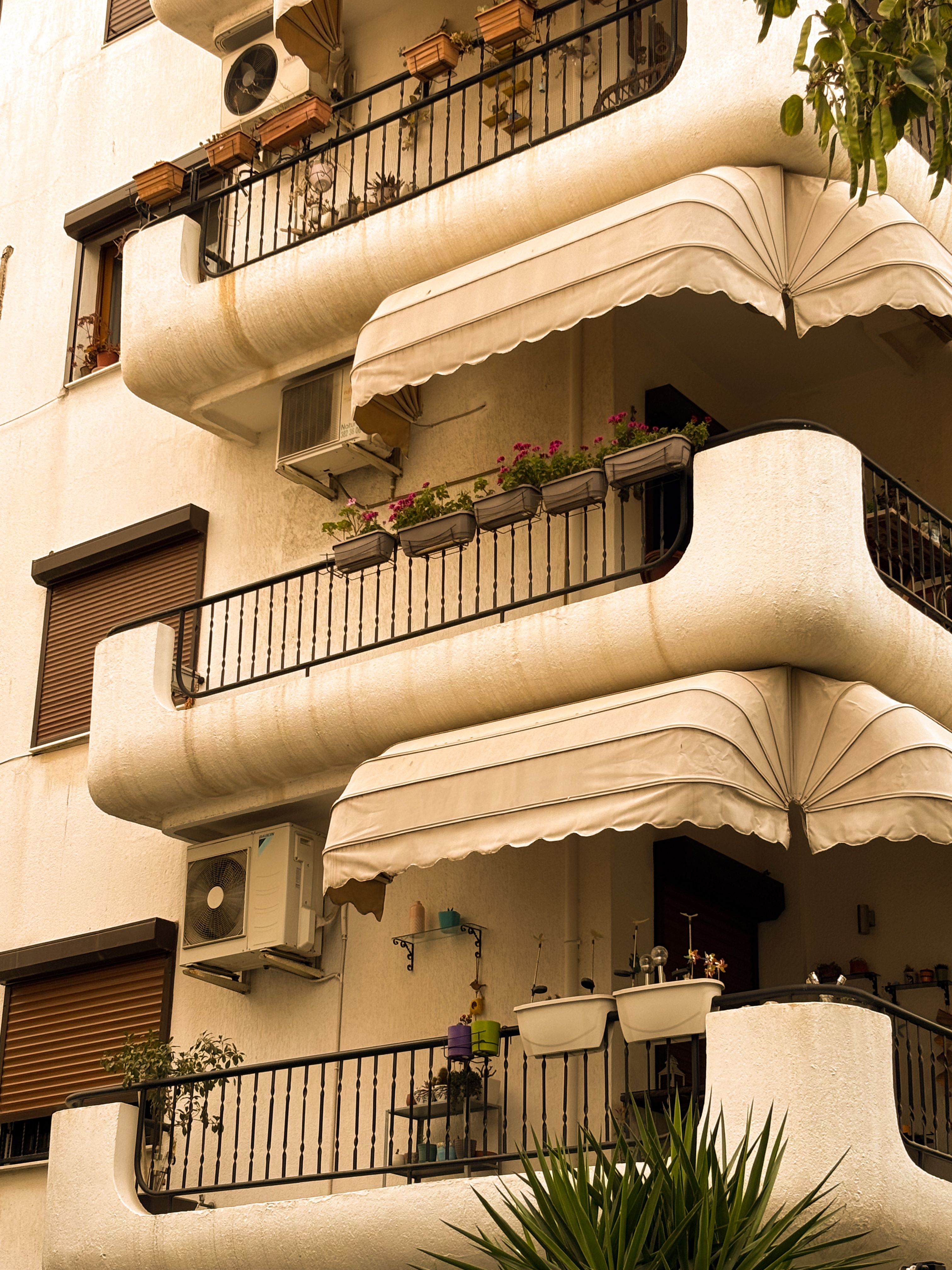Beige foldable sunshade clamped to a small apartment balcony railing on a sunny day