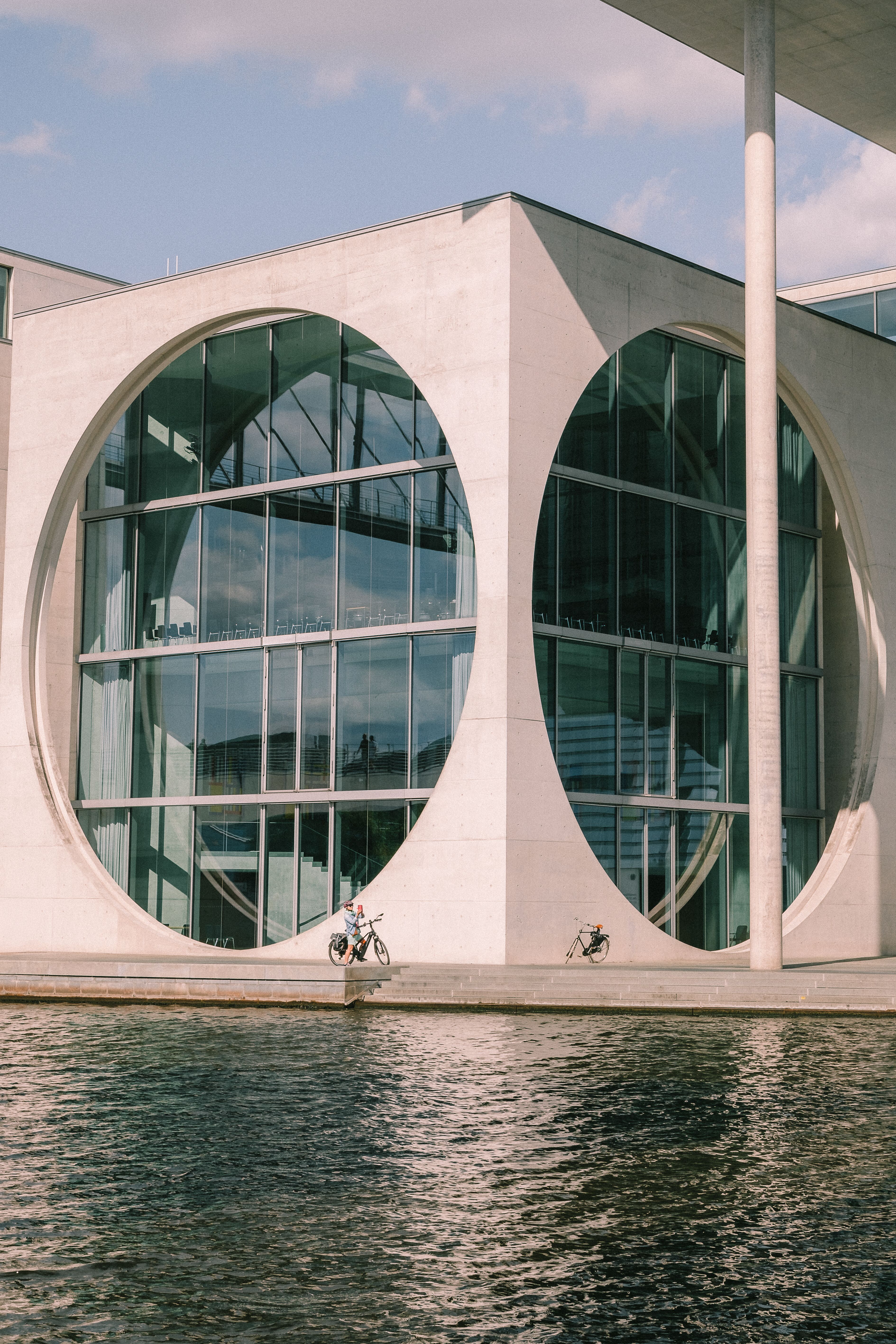 Exterior view of a modern government building in Berlin with circular windows and reflections.