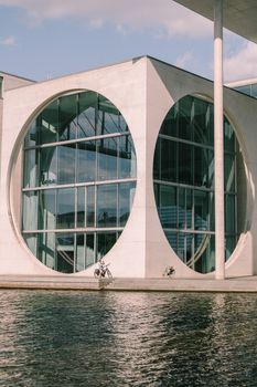 Exterior view of a modern government building in Berlin with circular windows and reflections.
