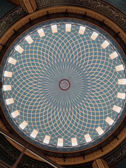Free Captivating view of an ornate mosque dome ceiling with geometric patterns and calligraphy. Stock Photo
