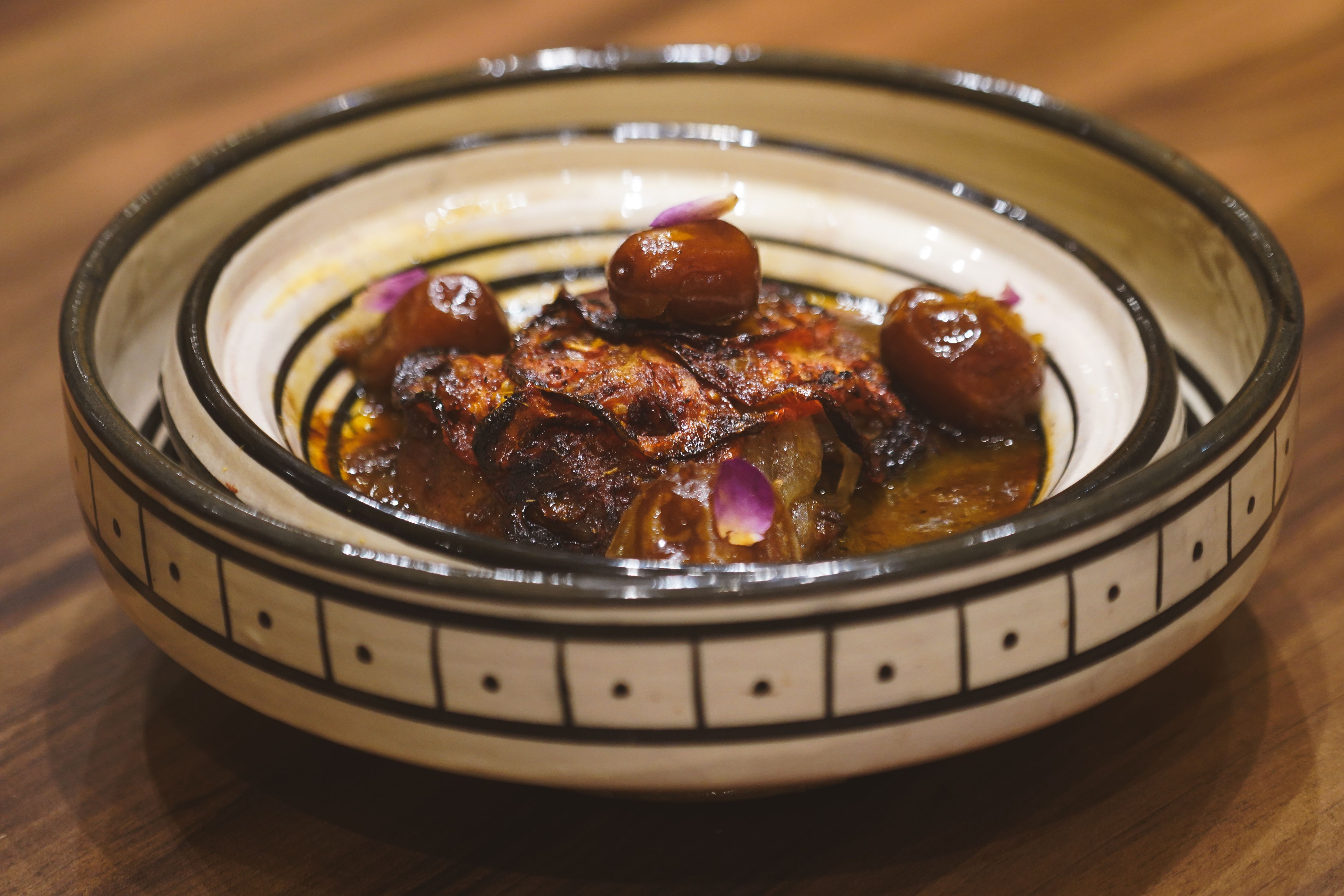 Delicious Moroccan tagine with dates served in an artisanal bowl, showcasing vibrant flavors of Essaouira, Morocco.