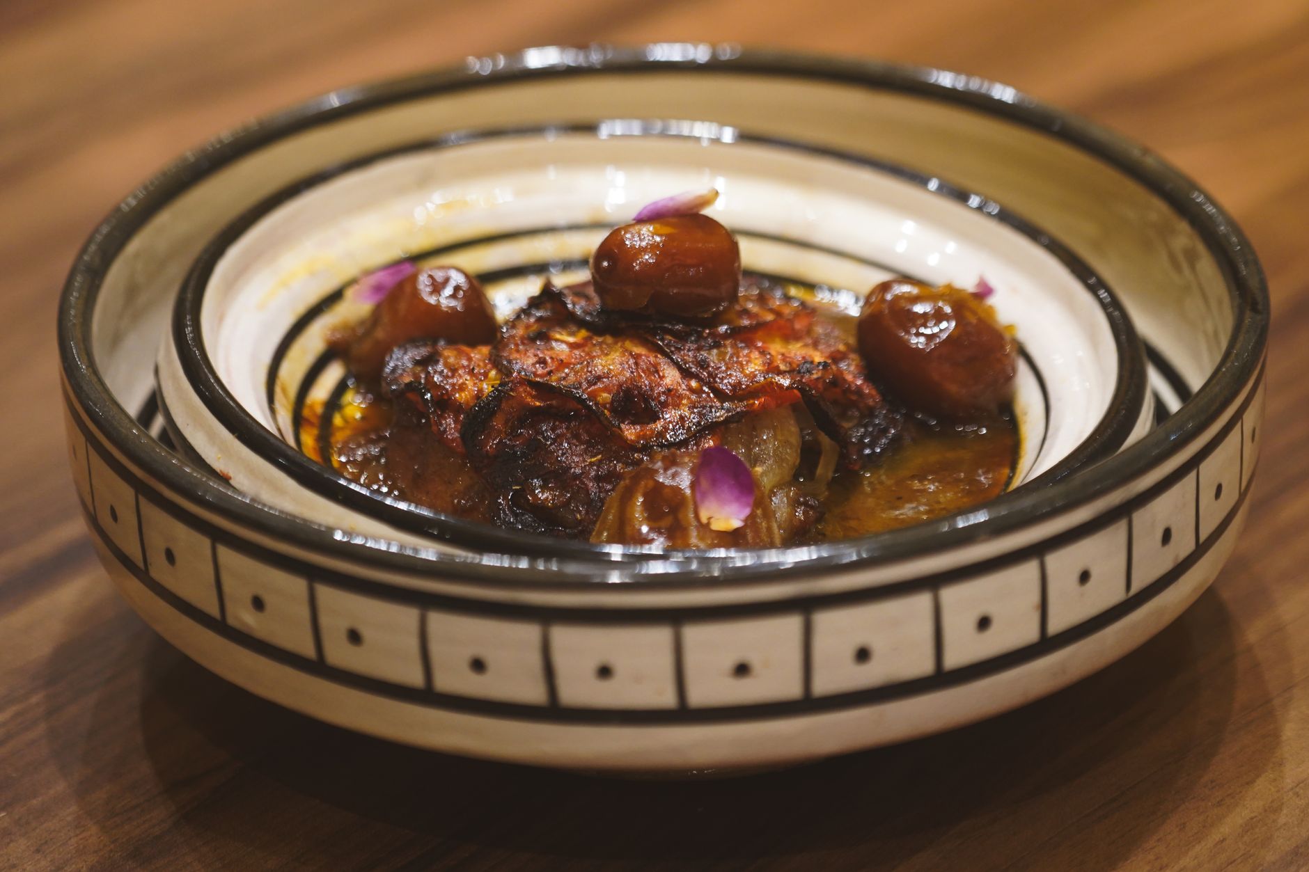 Photo : Msaidi Art / Pexels Delicious Moroccan tagine with dates served in an artisanal bowl, showcasing vibrant flavors of Essaouira, Morocco.